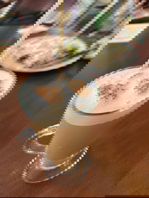 A cappuccino with cinnamon on top of a wooden table.
