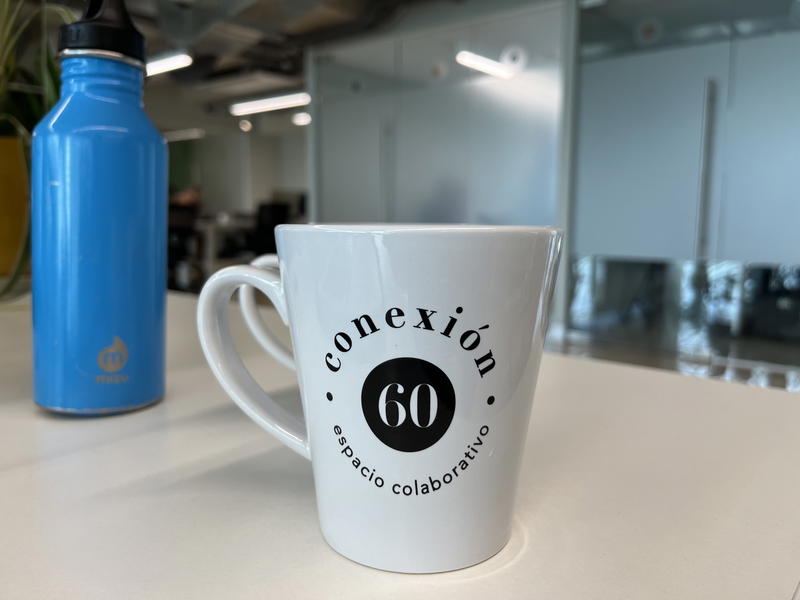 A coffee mug with the word 'conexion' on it sits on a desk in Merida, Mexico.
