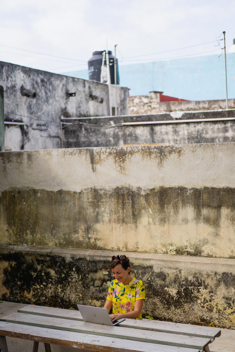 A woman sitting at a table in Merida, Mexico using a laptop.