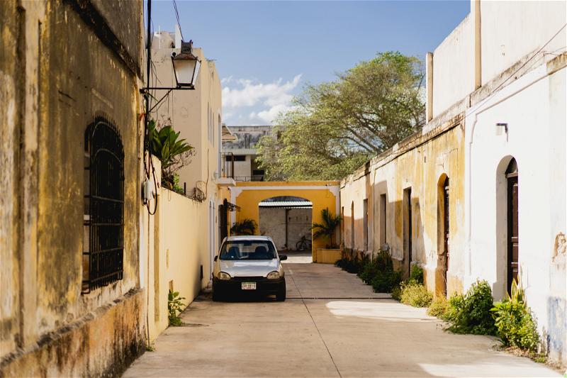 A narrow alleyway with a parked car in Mérida, Mexico.