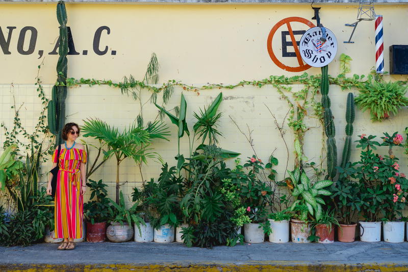 A woman standing in front of a wall of potted plants in Mexico.