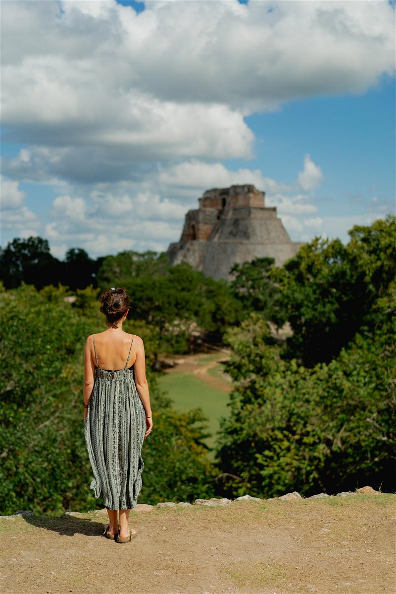 A woman in a dress is standing on a hill overlooking the jungle in Mexico.