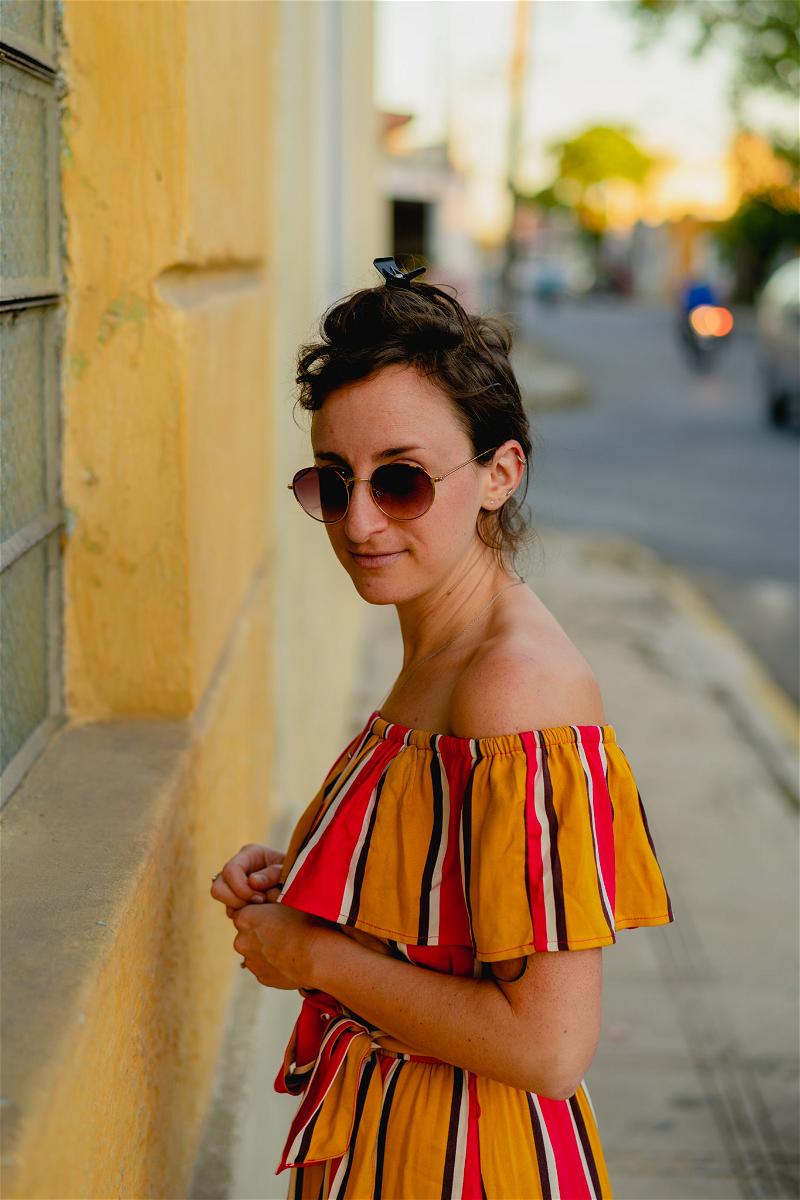 A woman in a striped dress leaning against a wall in Merida, Mexico.
