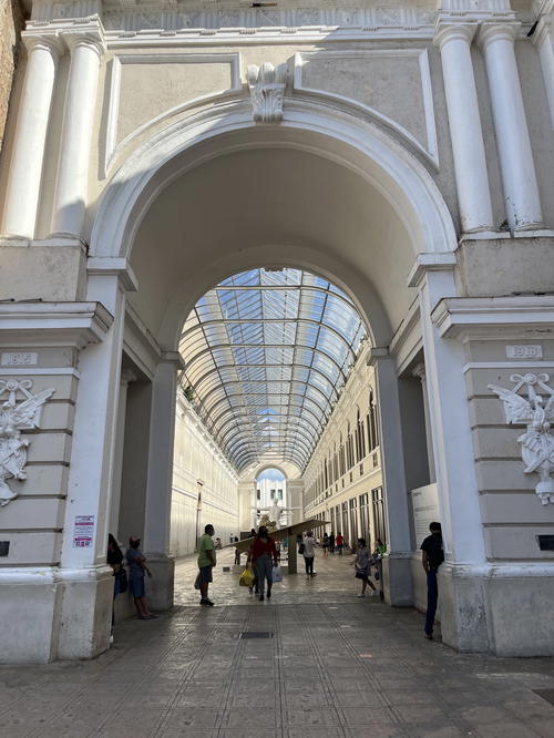 An archway in Merida, Mexico with people walking through it.