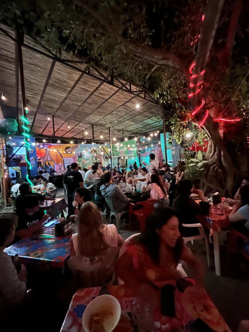 A group of people sitting at tables in a restaurant in Merida, Mexico at night.