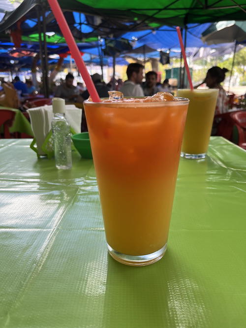 A glass of orange juice with a straw from Mexico sitting on a table in Merida.