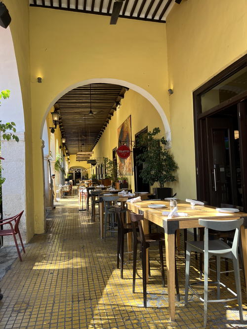 A restaurant in Merida, Mexico with tables and chairs in a yellow building.