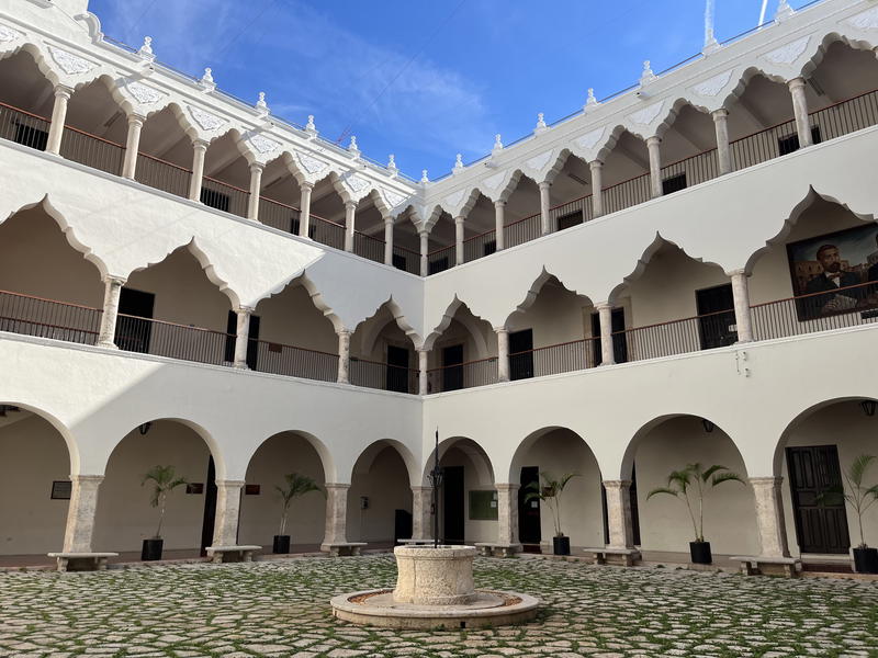 A courtyard in Merida, Mexico adorned with arches and a fountain.