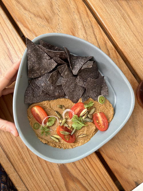 A person holding a bowl of hummus and chips in Merida, Mexico.