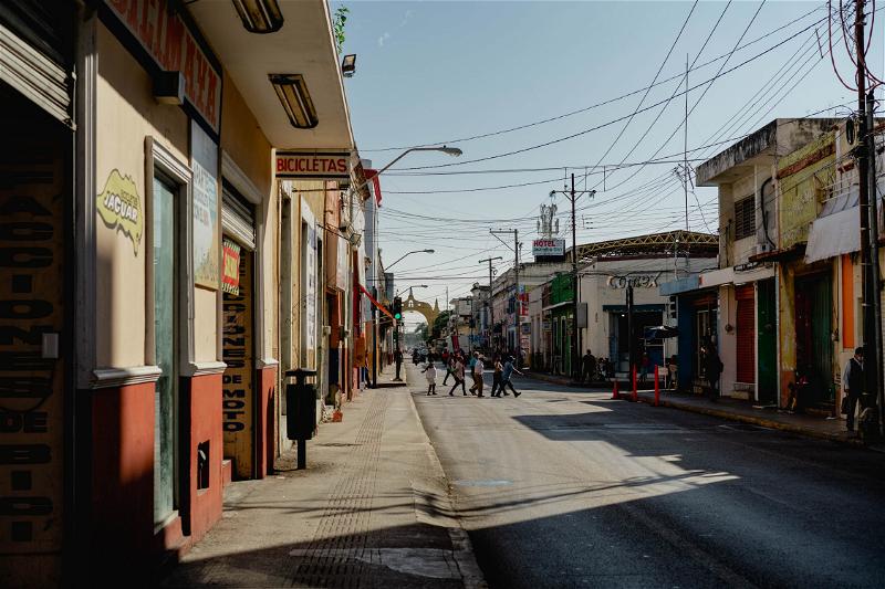 A street in Merida, Mexico with people walking down it.