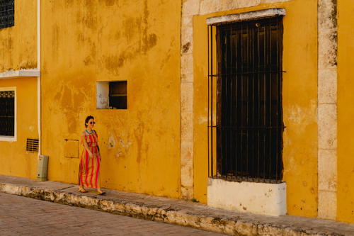 A woman standing in front of a yellow building in Merida, Mexico.