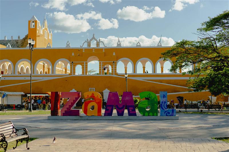 A colorful sign in front of a yellow building in Merida, Mexico.