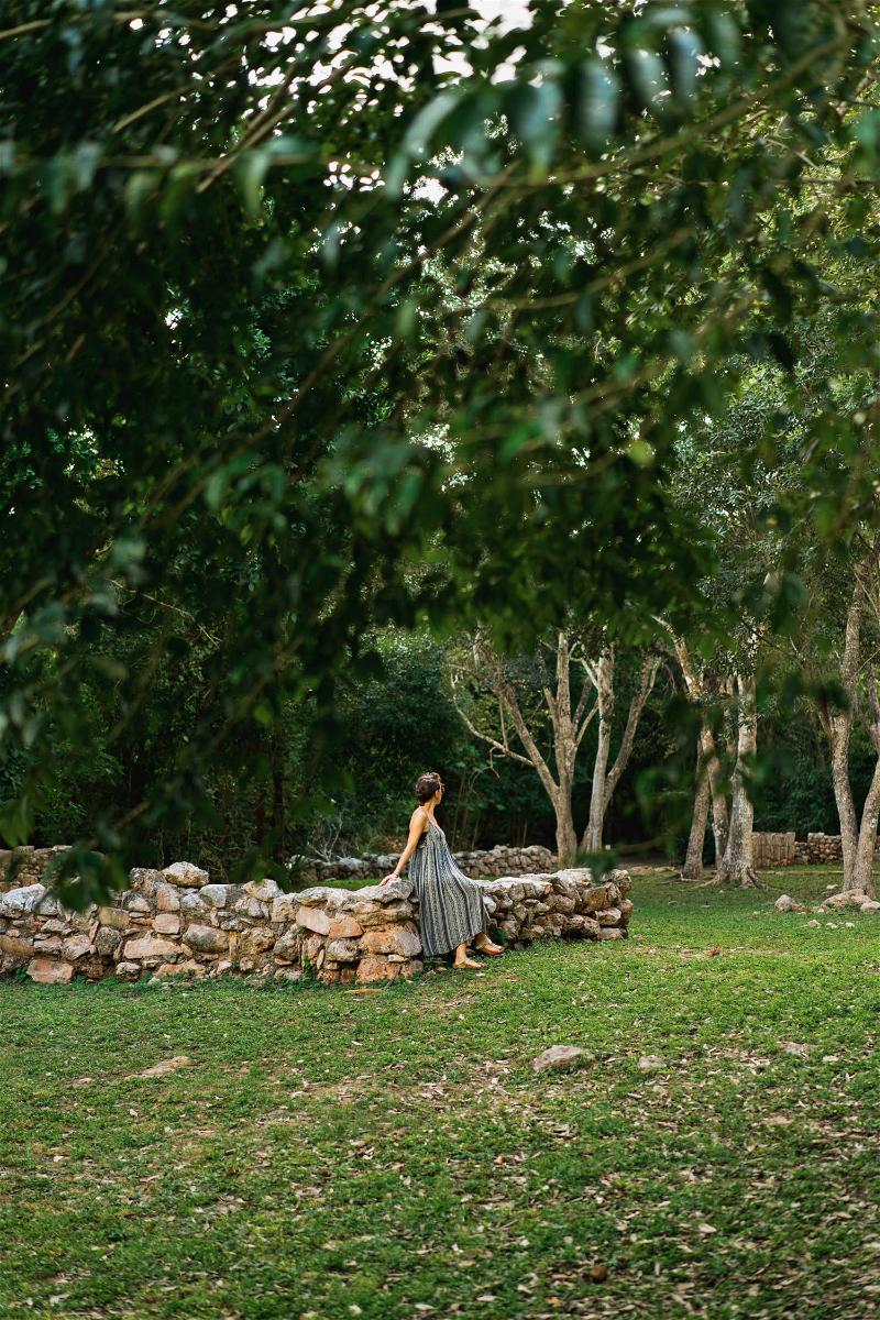 A woman in a dress walking through the grassy area of Merida, Mexico.