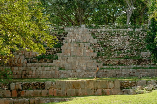 A man is standing in front of a large stone structure in Merida, Mexico.