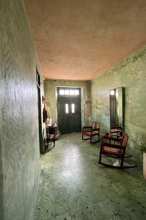A vibrant hallway in Merida, Mexico with green walls and a rocking chair.