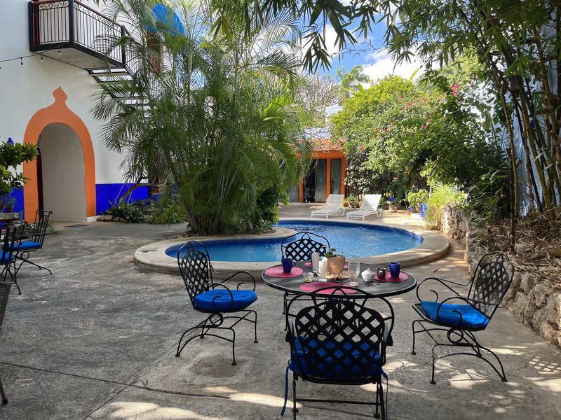 A patio in Merida, Mexico adorned with blue chairs and a refreshing pool.