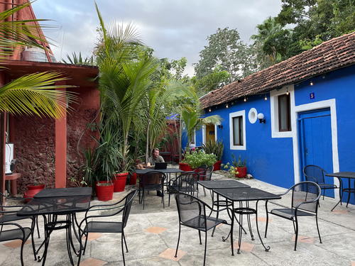 A courtyard with tables and chairs in a blue building in Merida, Mexico.