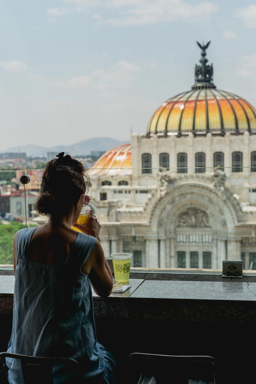 a woman sitting on a balcony looking out at the city