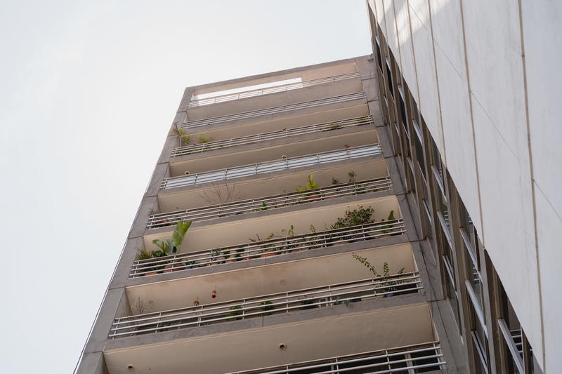 a tall building with a bunch of plants on the balcony