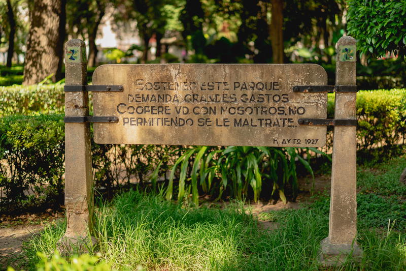 a wooden sign in front of some bushes