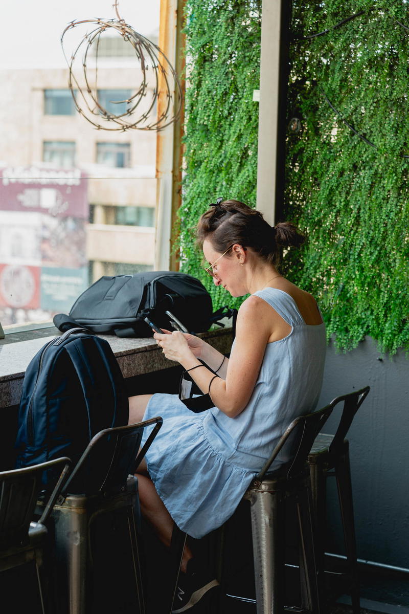 A woman sitting at a table in Mexico City looking at her cell phone.