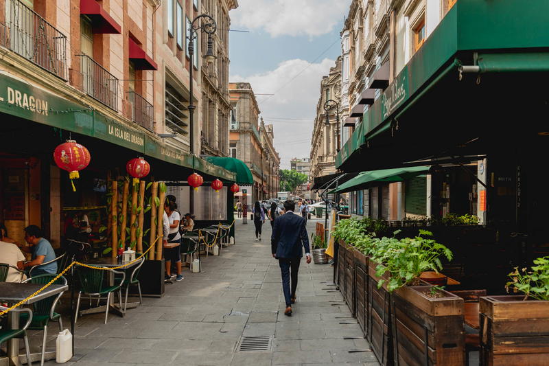 A man walking down a narrow street in Mexico City.