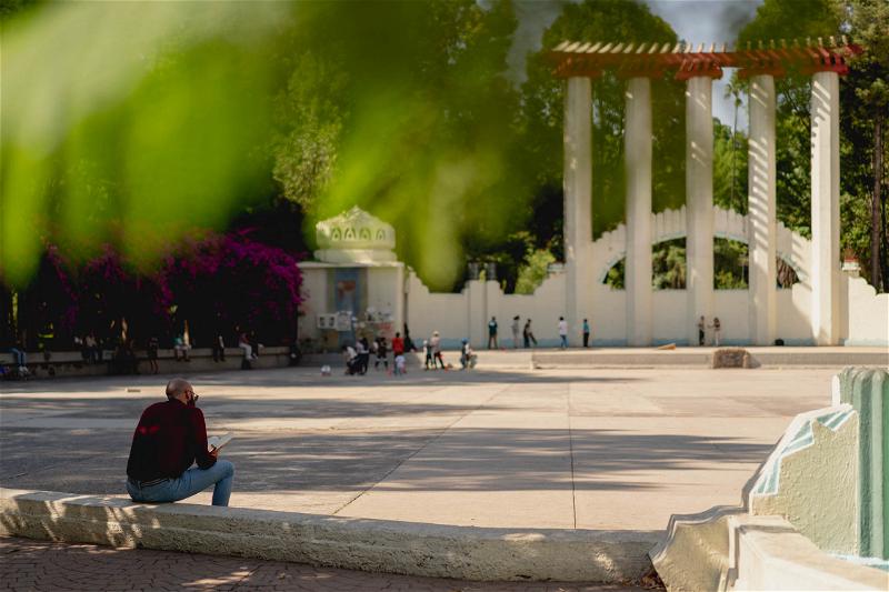 A person sitting on a bench near a fountain in Mexico City.