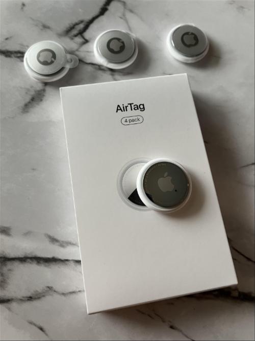 An Apple Airtag 4 pack box with four AirTags on top of it.