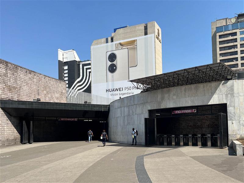 The entrance to a subway station in Mexico City with a large building in the background.