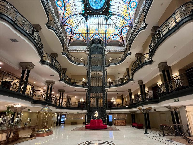 The lobby of a large building in Mexico City with a stained glass ceiling.