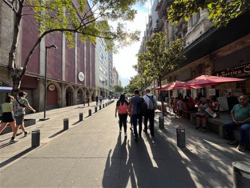 People walking down a sidewalk in Mexico City.