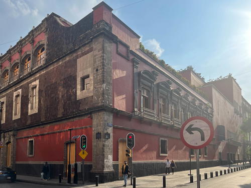A red building in Mexico City with a street sign in front of it.