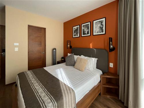 A Mexico City hotel room with orange walls and a bed.