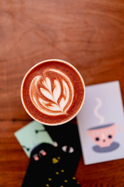 A cup of coffee from Mexico City with latte art on top of a wooden table.