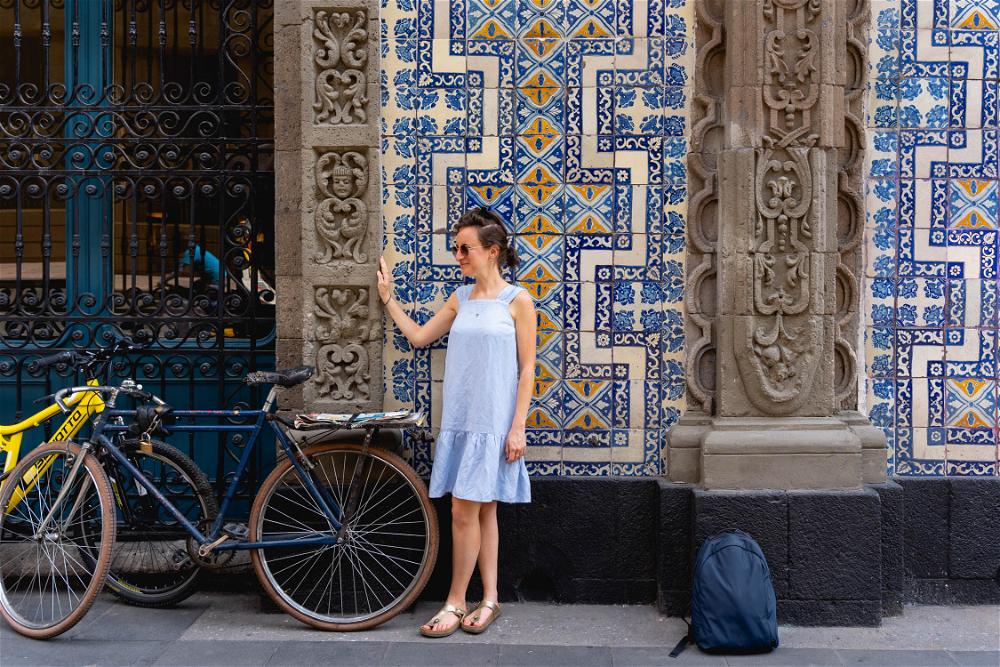 A woman in a blue dress standing next to a bicycle in Mexico City.