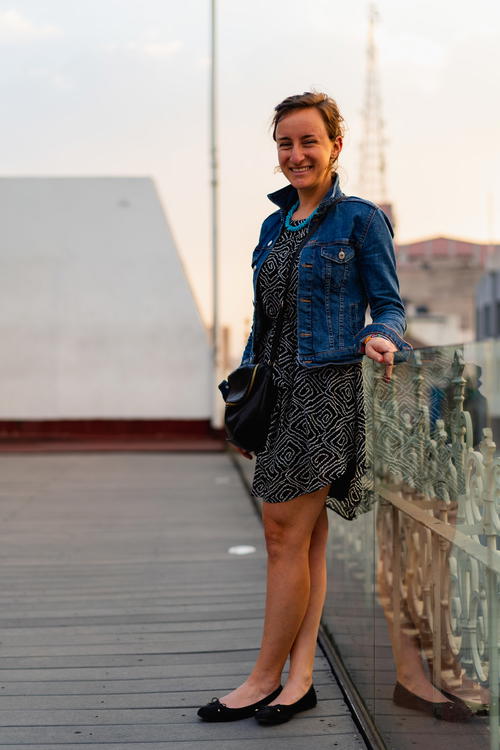 A woman wearing a denim jacket standing on a railing in Mexico City.