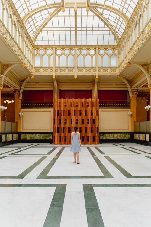 A woman in a dress standing in a large hall in Mexico City.