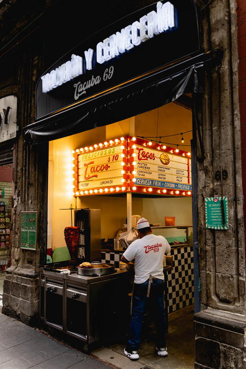 A man standing in front of a restaurant in Mexico City, Mexico.