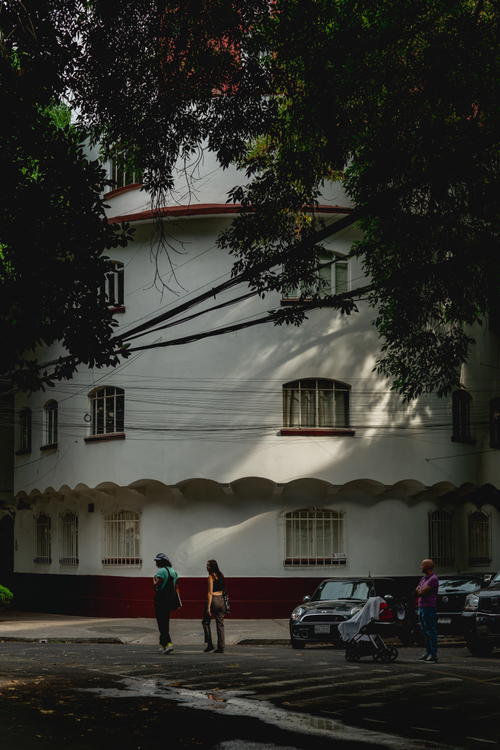 a person walking down a street in front of a white building