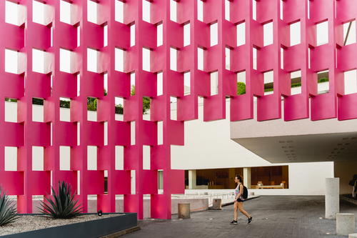 a person walking in front of a pink building