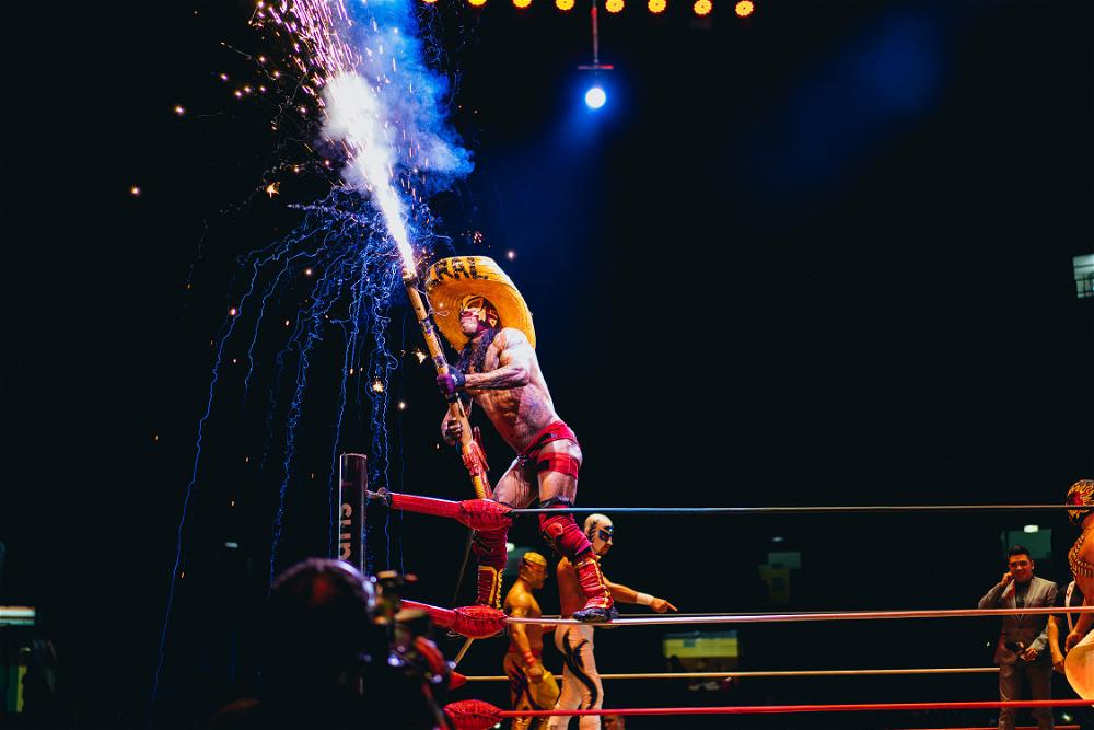 A wrestler in Mexico City holding a firework.