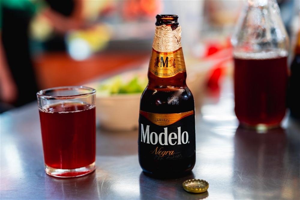 A bottle of Modelo beer from Mexico City sits on a table next to a glass.