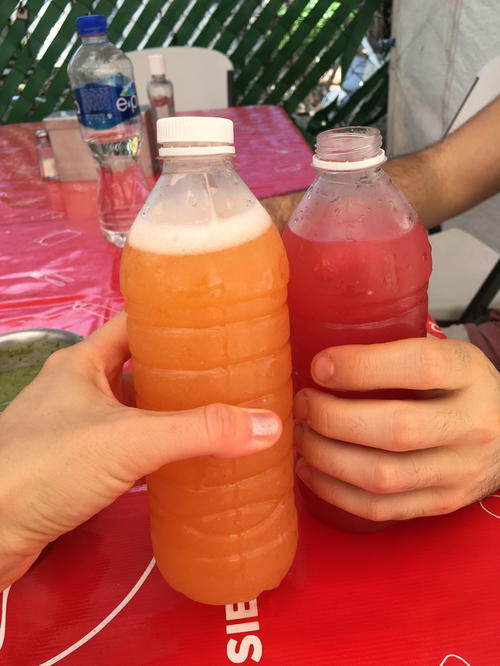 Two people holding bottles of juice at a table in Tulum.
