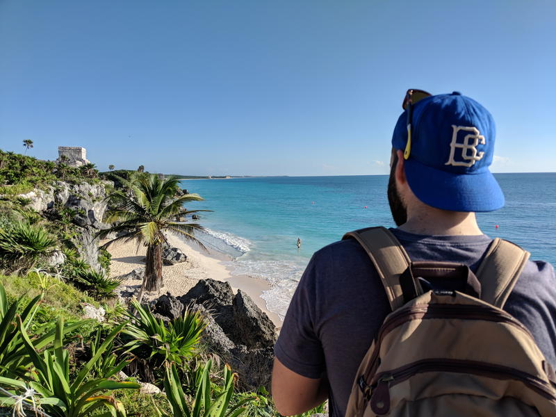 A man wearing a blue hat is looking at the beach in Mexico.