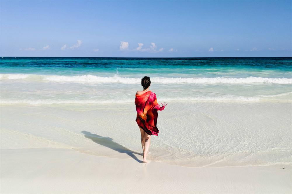 Woman on the beach with a red scarf in Tulum, Mexico