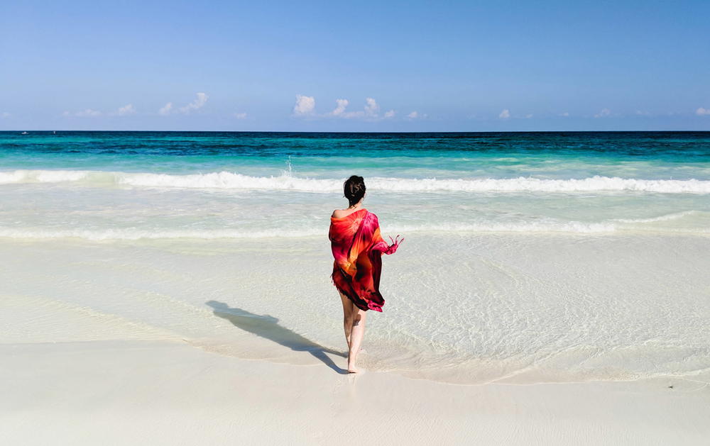 Woman on the beach with a red scarf in Tulum, Mexico