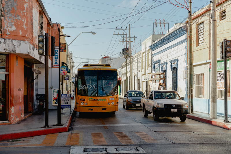 A yellow bus driving down a street in Uxmal, Mexico.