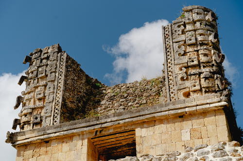 A stone building in Uxmal, Mexico with a cloudy sky.
