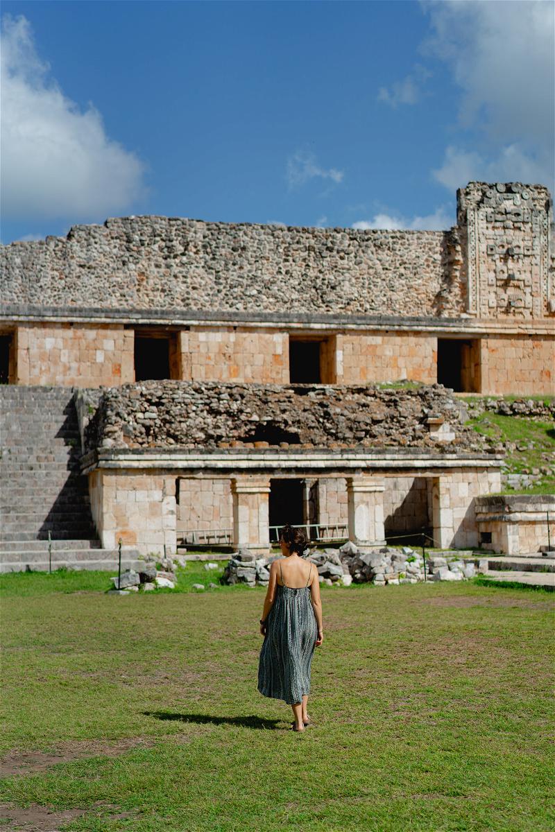 A woman walking in front of a building in Uxmal, Mexico.