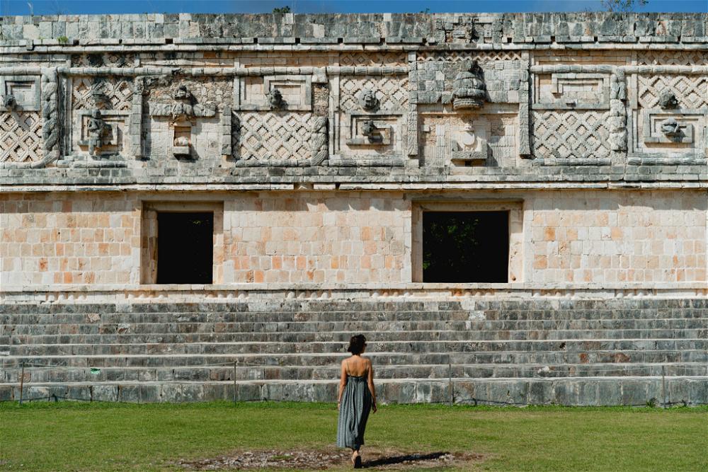 A woman standing in front of an ancient building in Uxmal, Mexico.